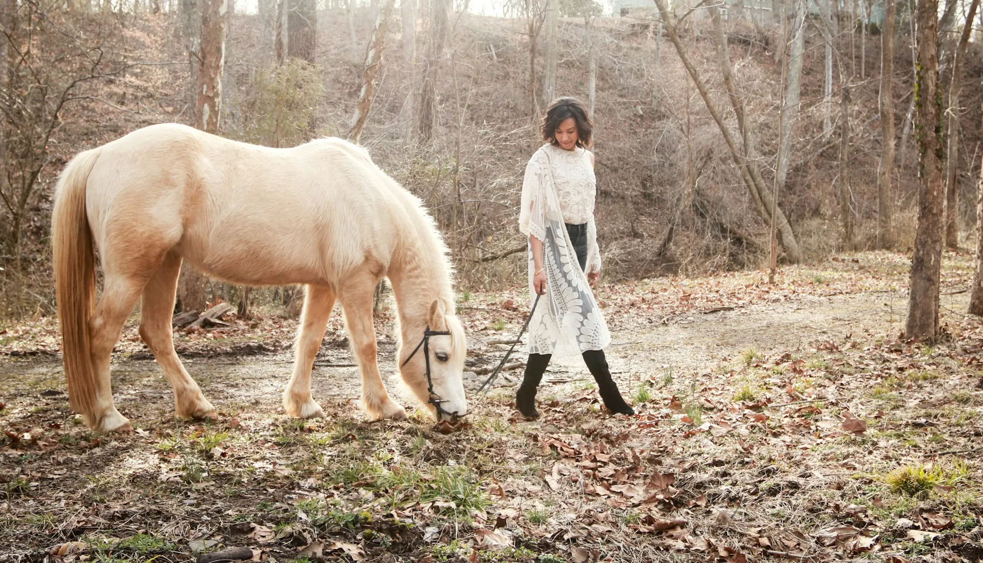 A woman walking beside a palomino horse